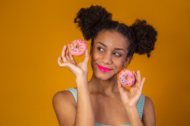 Giovane bella donna afro con una ciambella