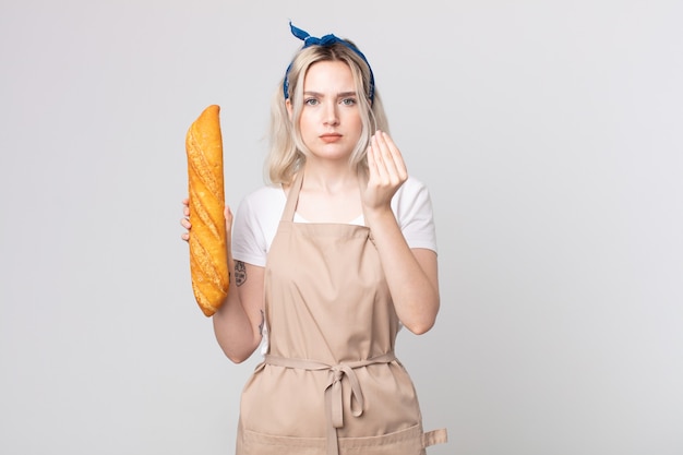 Giovane bella donna albina che fa un gesto di denaro o di denaro, dicendoti di pagare con una baguette di pane