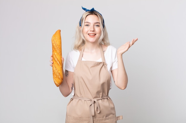 Giovane bella donna albina che si sente felice, sorpresa di realizzare una soluzione o un'idea con una baguette di pane