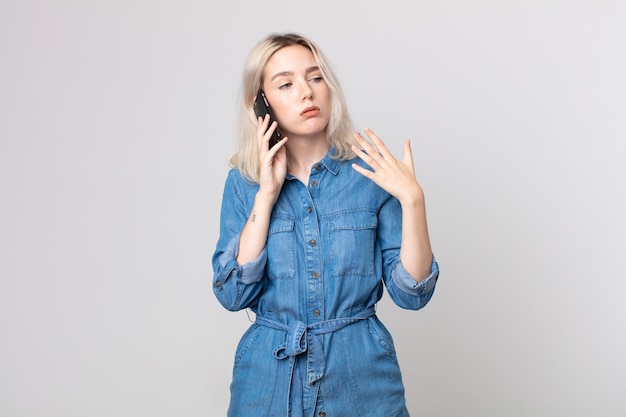 Giovane bella donna albina che si sente stressata, ansiosa, stanca e frustrata e parla con uno smartphone