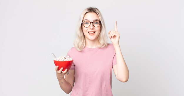 Giovane bella donna albina che si sente un genio felice ed eccitato dopo aver realizzato un'idea con una ciotola per la colazione