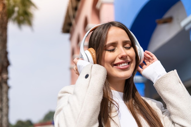 Giovane bella donna all'aperto ascoltando musica e cantando