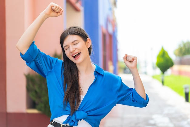 Giovane bella donna all'aperto che celebra una vittoria