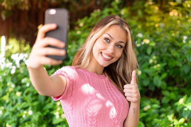 Giovane bella donna all'aperto che fa un selfie con il cellulare