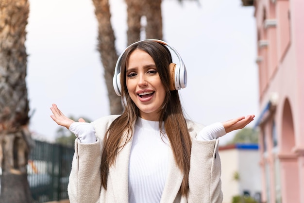 Giovane bella donna all'aperto sorpresa e ascoltando musica