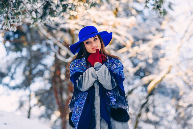 Giovane bella donna alla moda in cappello blu e sciarpa che camminano nel parco