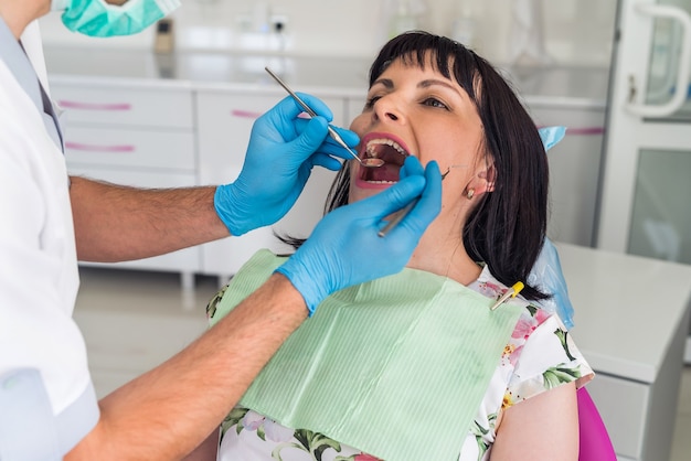 Giovane bella donna alla revisione del dentista.