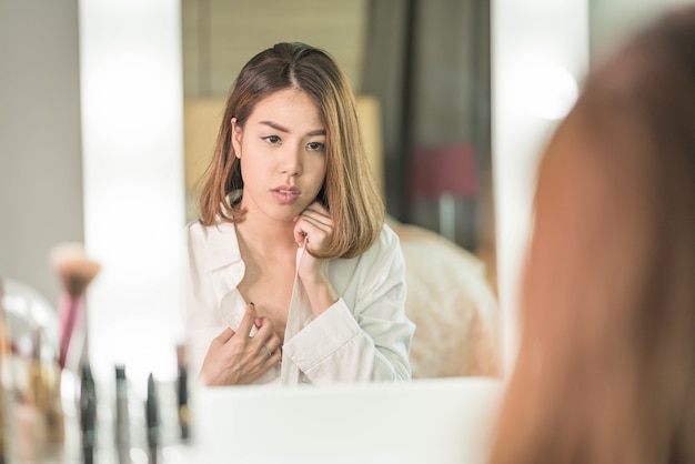 Giovane bella donna asiatica che fa trucco vicino allo specchio