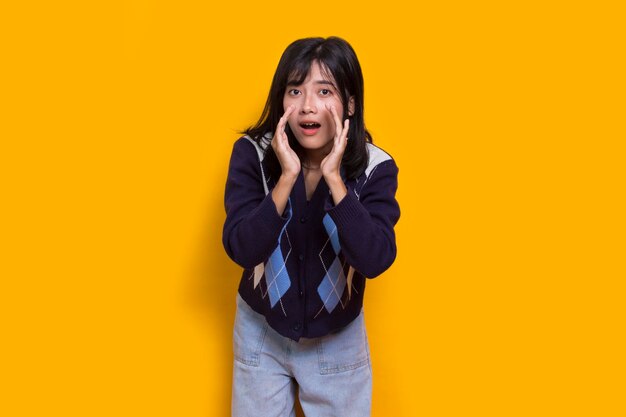giovane bella donna asiatica che grida e urla annunciando isolato su sfondo giallo