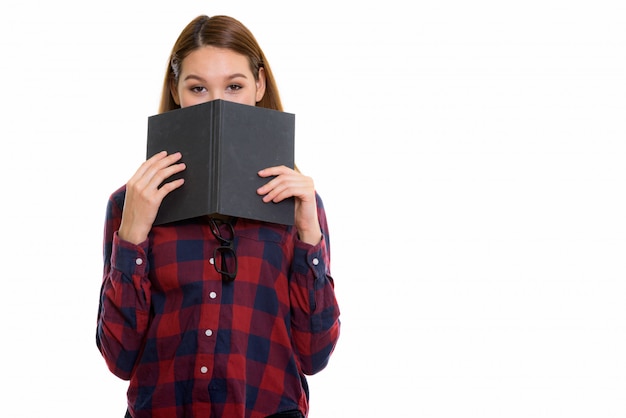 Giovane bella donna asiatica che si nasconde dietro il libro isolato