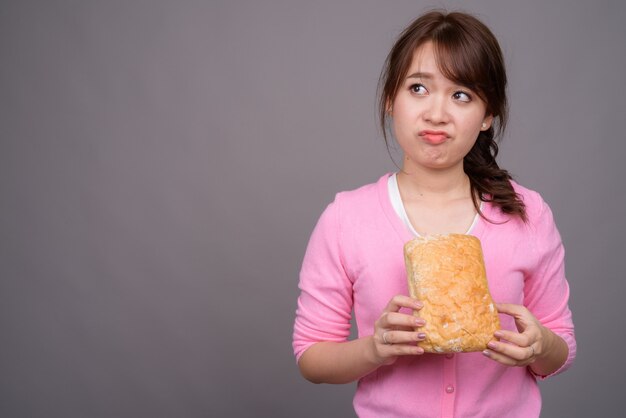 Giovane bella donna asiatica che tiene pezzo di pane