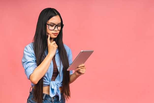 Giovane bella donna asiatica che utilizza tablet gadget computer ipad Concetto di stile di vita isolato su sfondo rosa