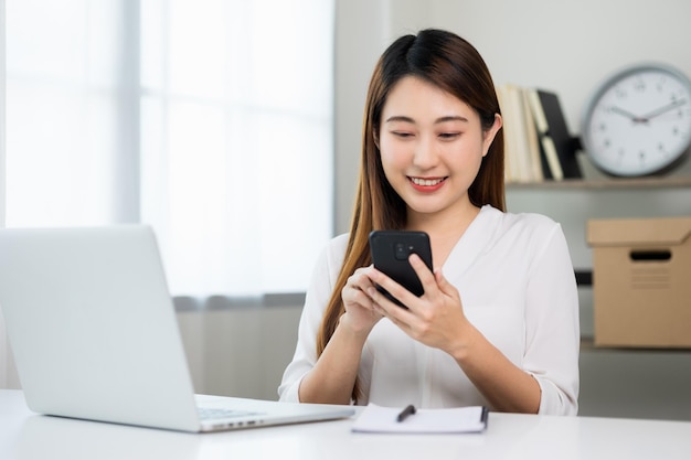 Giovane bella donna asiatica di affari che utilizza smartphone. Sorridente affascinante felice giovane femmina sms toccando sul display del telefono cellulare.