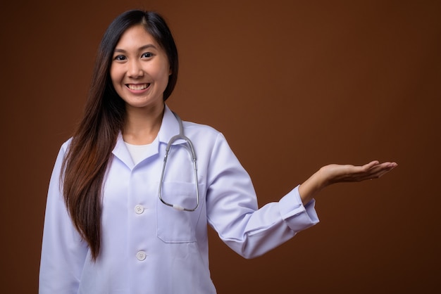 Giovane bella donna asiatica medico su sfondo marrone
