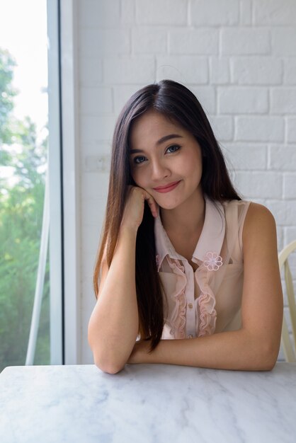Giovane bella donna asiatica rilassante presso la caffetteria