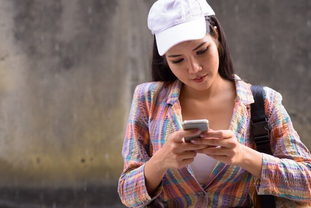 Giovane bella donna asiatica utilizzando il telefono cellulare all'aperto