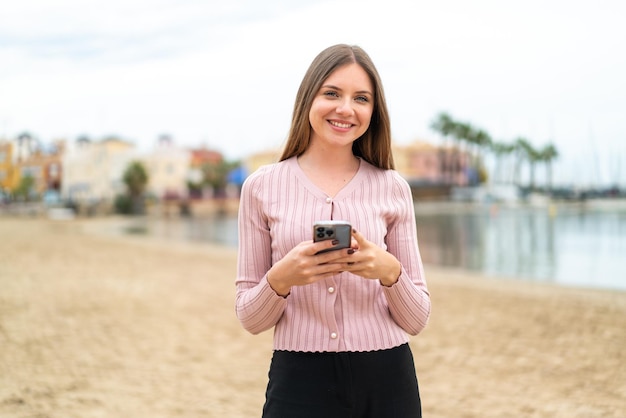 Giovane bella donna bionda che invia un messaggio con il cellulare