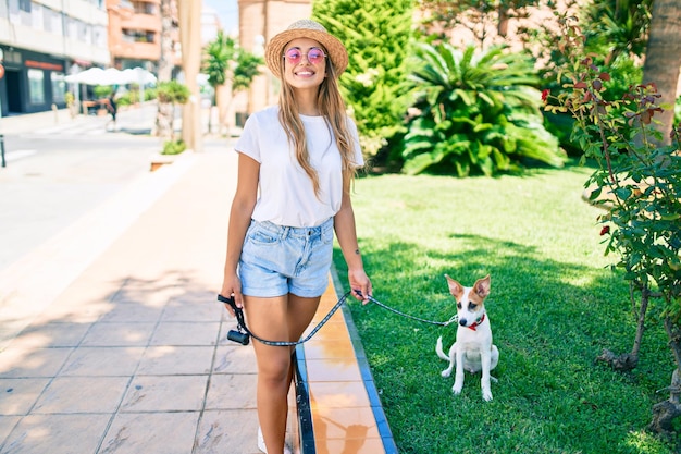 Giovane bella donna bionda che porta a spasso il cane fuori in una giornata estiva