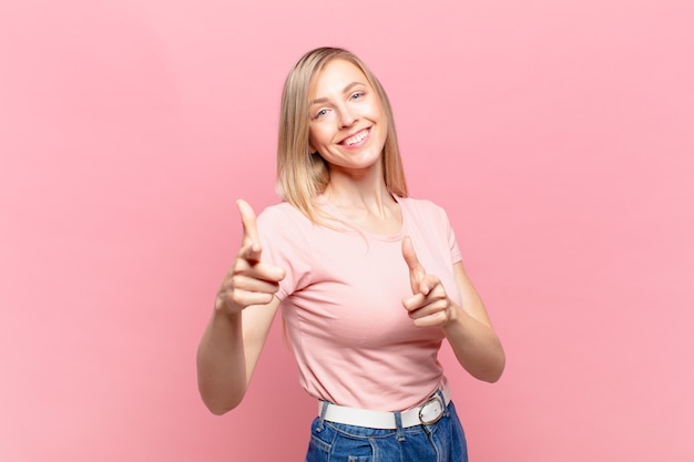 Giovane bella donna bionda che si sente felice, fresca, soddisfatta, rilassata e di successo, indicando la telecamera, scegliendo te