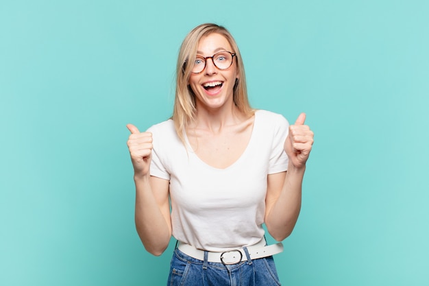 Giovane bella donna bionda che si sente scioccata, eccitata e felice, ridendo e celebrando il successo, dicendo wow!