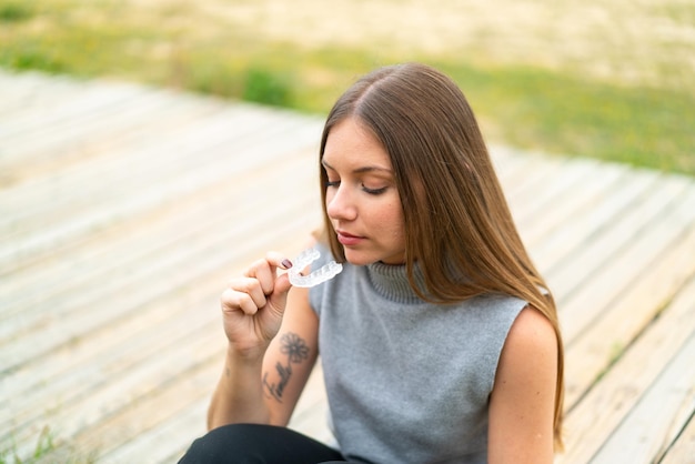 Giovane bella donna bionda che tiene le parentesi graffe invisibili