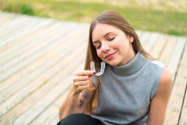 Giovane bella donna bionda che tiene le parentesi graffe invisibili