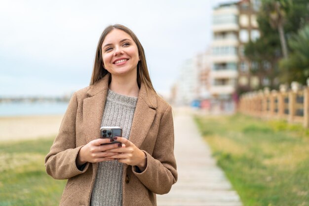 Giovane bella donna bionda che utilizza il telefono cellulare e cerca