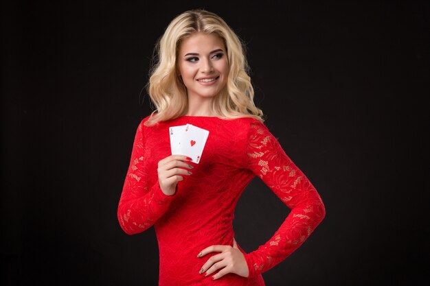 Giovane bella donna bionda con carte da gioco su poker nero