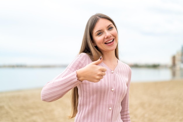 Giovane bella donna bionda con i pollici in su perché è successo qualcosa di buono