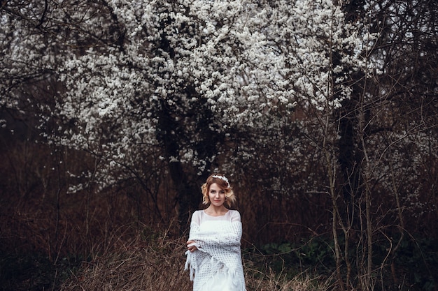 Giovane bella donna bionda in giardino fiorito. Sposa.