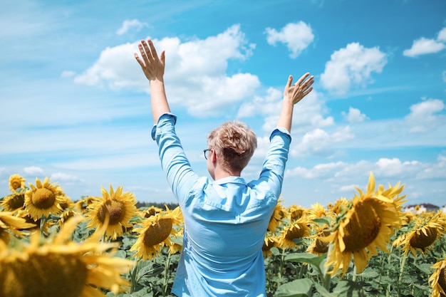 Giovane bella donna bionda in piedi nel campo di girasoli