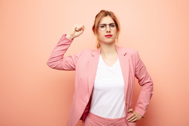 Giovane bella donna bionda sentendosi seria, forte e ribelle, alzando il pugno, protestando o combattendo per la rivoluzione. concetto di affari