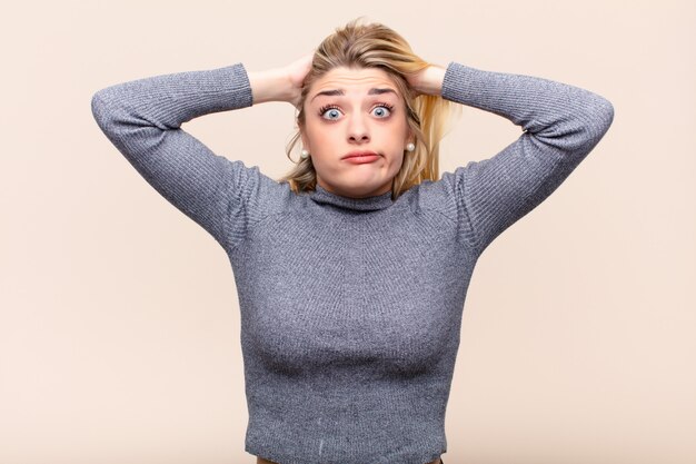 Giovane bella donna bionda sentirsi stressato con le mani sulla testa