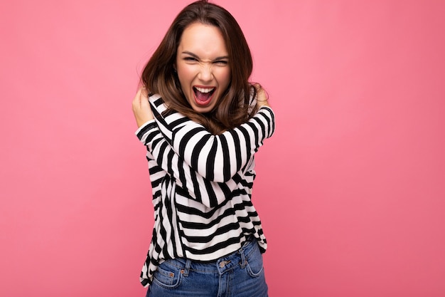 Giovane bella donna bruna signora alla moda in una donna positiva a maniche lunghe a righe casual mostra il viso