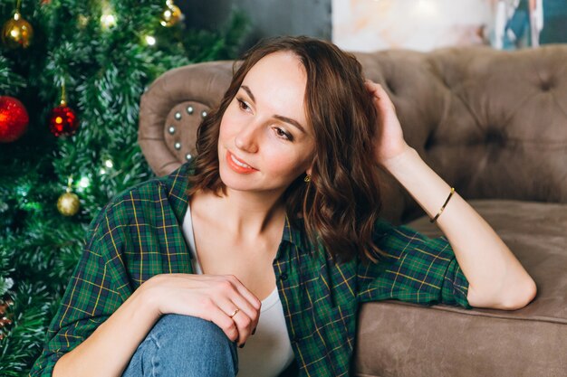 Giovane bella donna castana all'albero di Natale