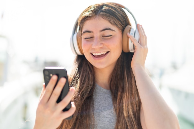 Giovane bella donna caucasica che ascolta musica con un cellulare e canta