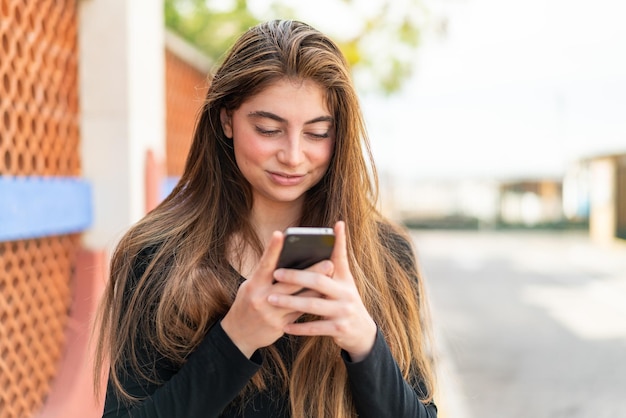 Giovane bella donna caucasica che manda un messaggio con il cellulare