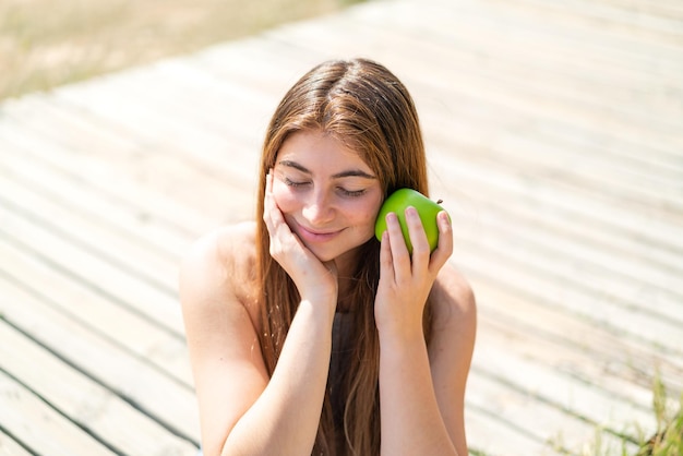 Giovane bella donna caucasica che tiene una mela con un'espressione felice