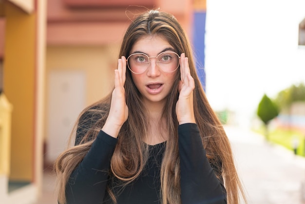 Giovane bella donna caucasica con gli occhiali e un'espressione sorpresa