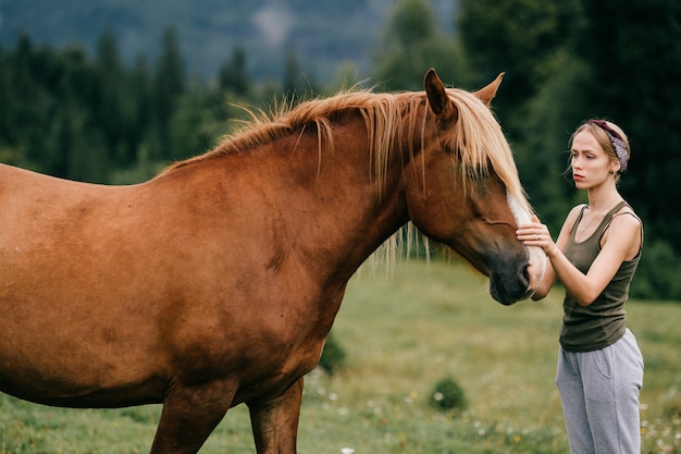 Giovane bella donna che abbraccia cavallo alla natura