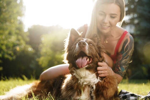 Giovane bella donna che accarezza il suo simpatico cane nel parco