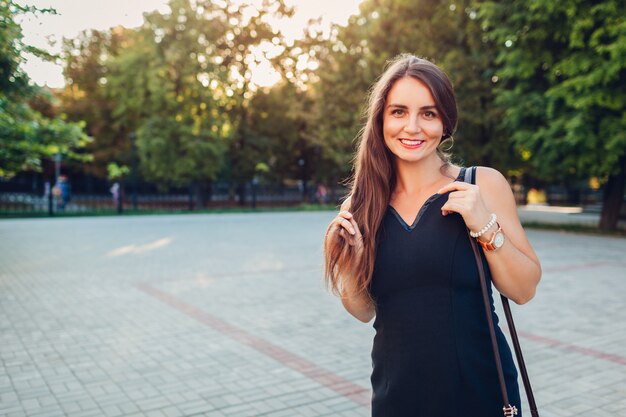 Giovane bella donna che cammina nel parco estivo. Elegante signora che indossa un vestito alla moda.