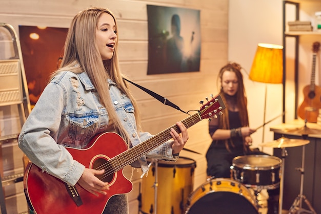 Giovane bella donna che canta mentre suona la chitarra e si esibisce con il suo gruppo