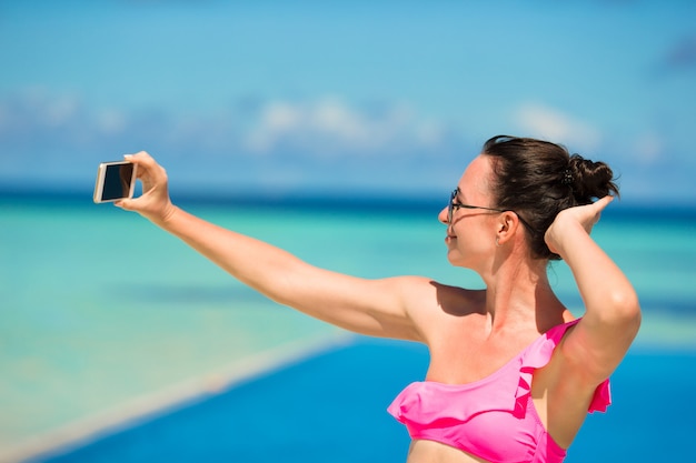 Giovane bella donna che cattura selfie con il telefono all&#39;aperto durante la vacanza al mare