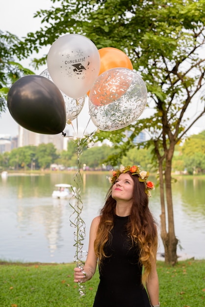 Giovane bella donna che celebra laurea al parco