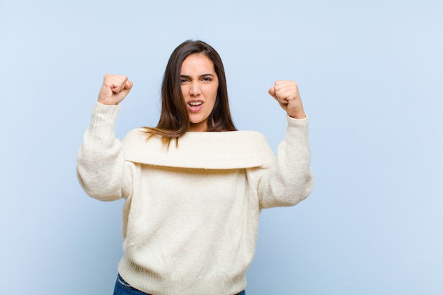 Giovane bella donna che celebra un incredibile successo come una vincitrice, che sembra entusiasta e felice di dire che prendilo! su sfondo blu