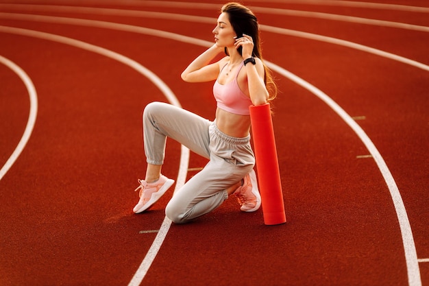 Giovane bella donna che fa stretching yoga allo stadio al tramonto Ora legale