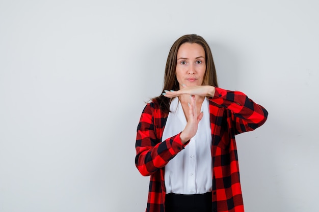 Giovane bella donna che mostra gesto di pausa temporale in abbigliamento casual e sembra sicura, vista frontale.