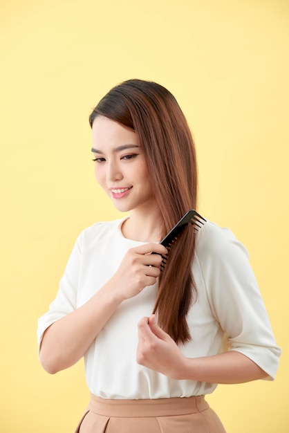 Giovane bella donna che pettina i suoi capelli in salone