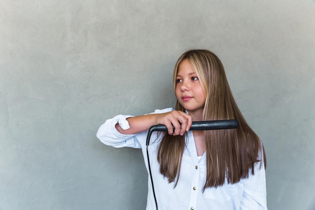 Giovane bella donna che raddrizza i suoi capelli lunghi